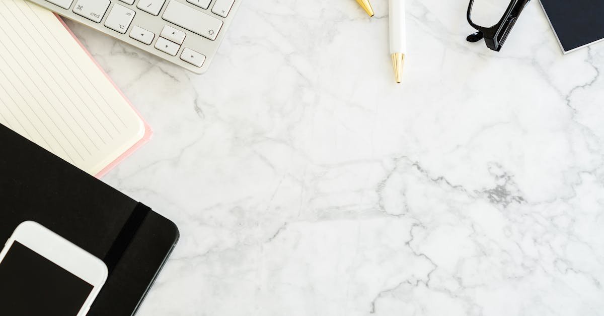 Flat lay of a modern office desk with gadgets and stationery on a marble surface.